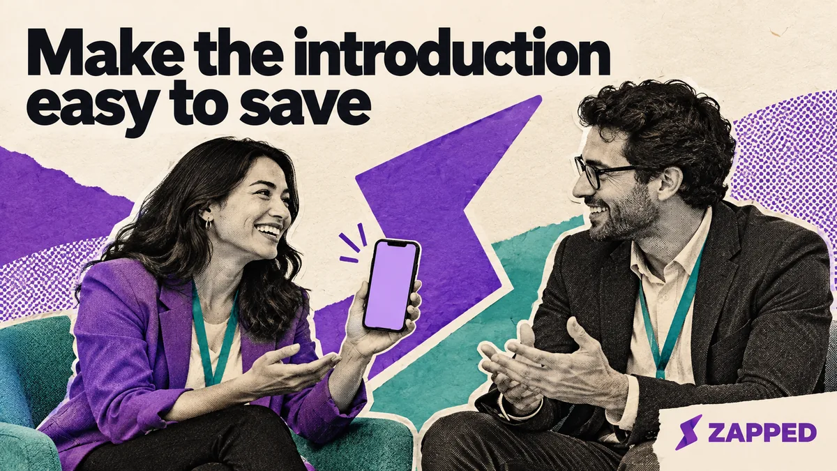 Two professionals talk at an event while one holds a phone between them.