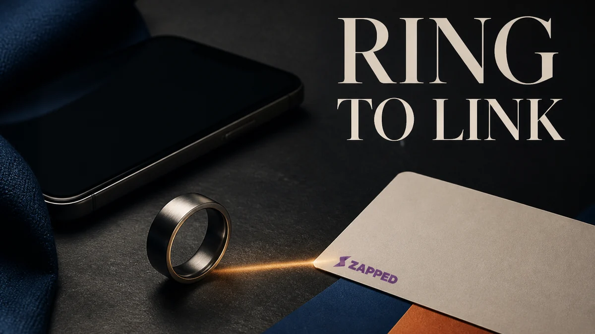 A minimal NFC ring beside a smartphone and a blank contact card at a networking table